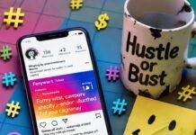 How to Promote Your Brand on Social Media Without Paid Ads Messy desk with chipped "Hustle or Bust" mug, phone, smiley note, colorful hashtags.